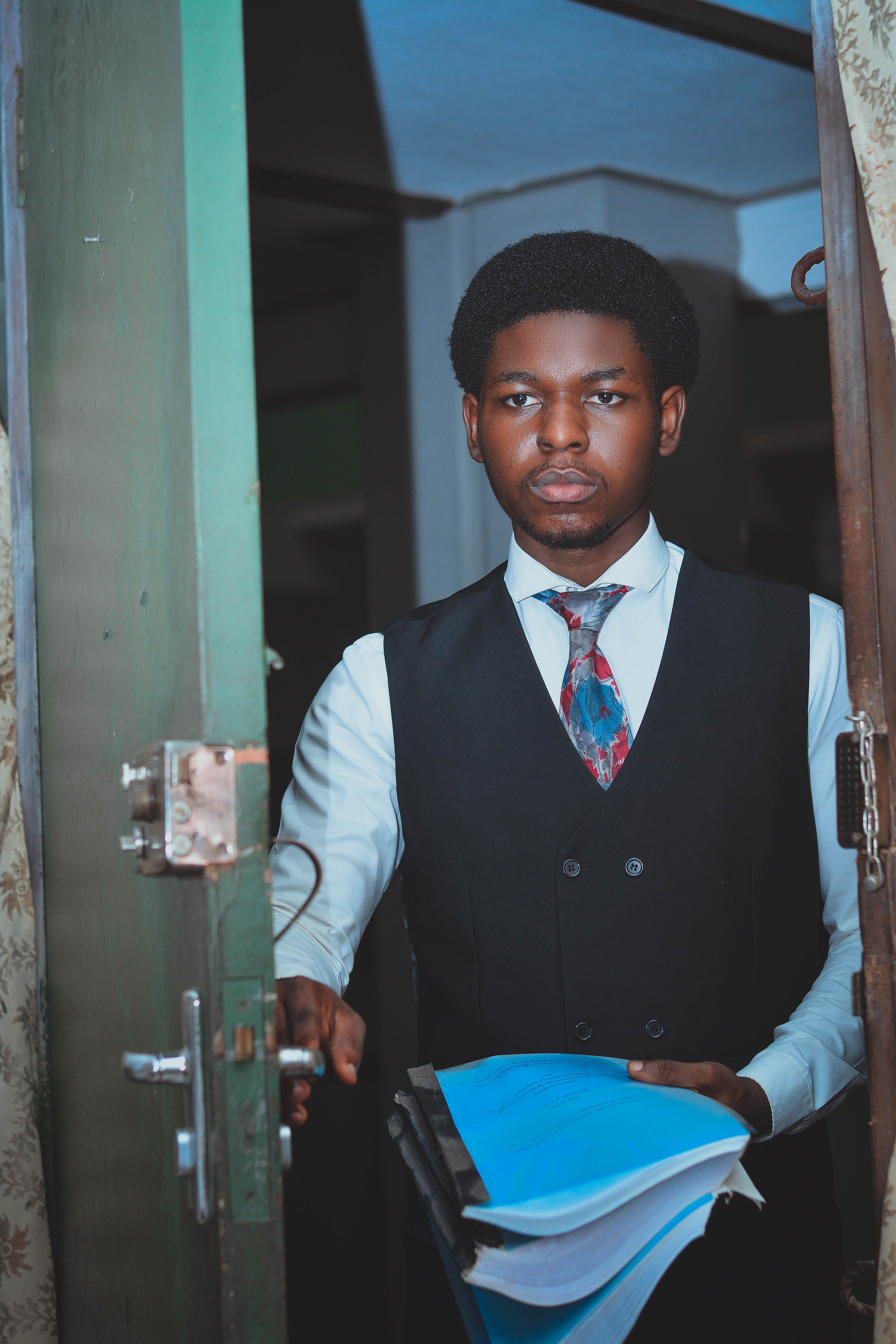Businessman in suit holding documents inside a room, ready for work or meeting.
