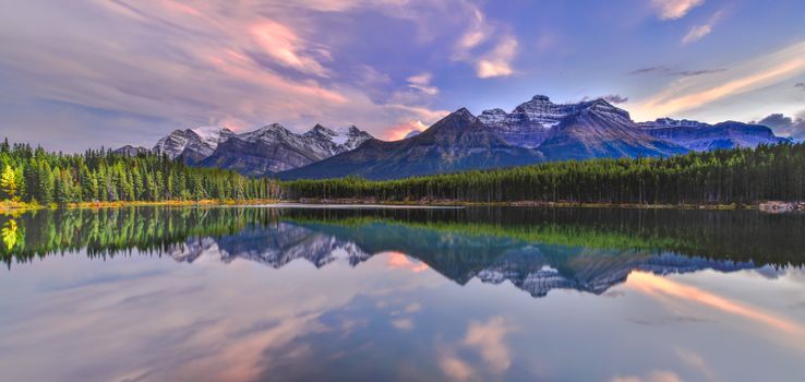 Stunning sunset reflection at Herbert Lake, with snow-capped Rockies in Banff National Park, Canada.