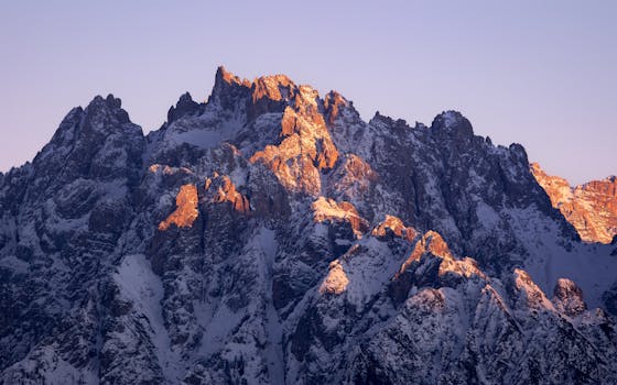 Majestic mountain range in Italy illuminated by sunset light, showcasing rugged beauty and natural splendor.