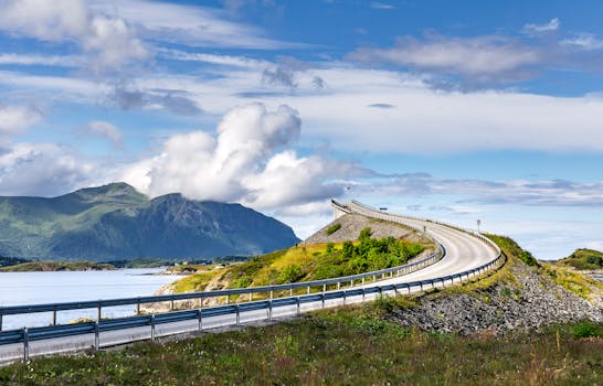 Beautiful coastal road curving through lush landscape on a sunny day in Norway.