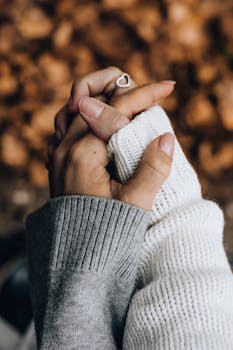 两只手穿着舒适的毛衣握在一起的特写，象征着秋天的爱与团结