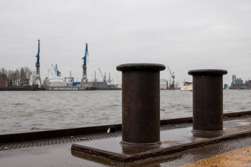 Free Rustic harbor view with bollards, cranes, and industrial backdrop in Hamburg. Stock Photo