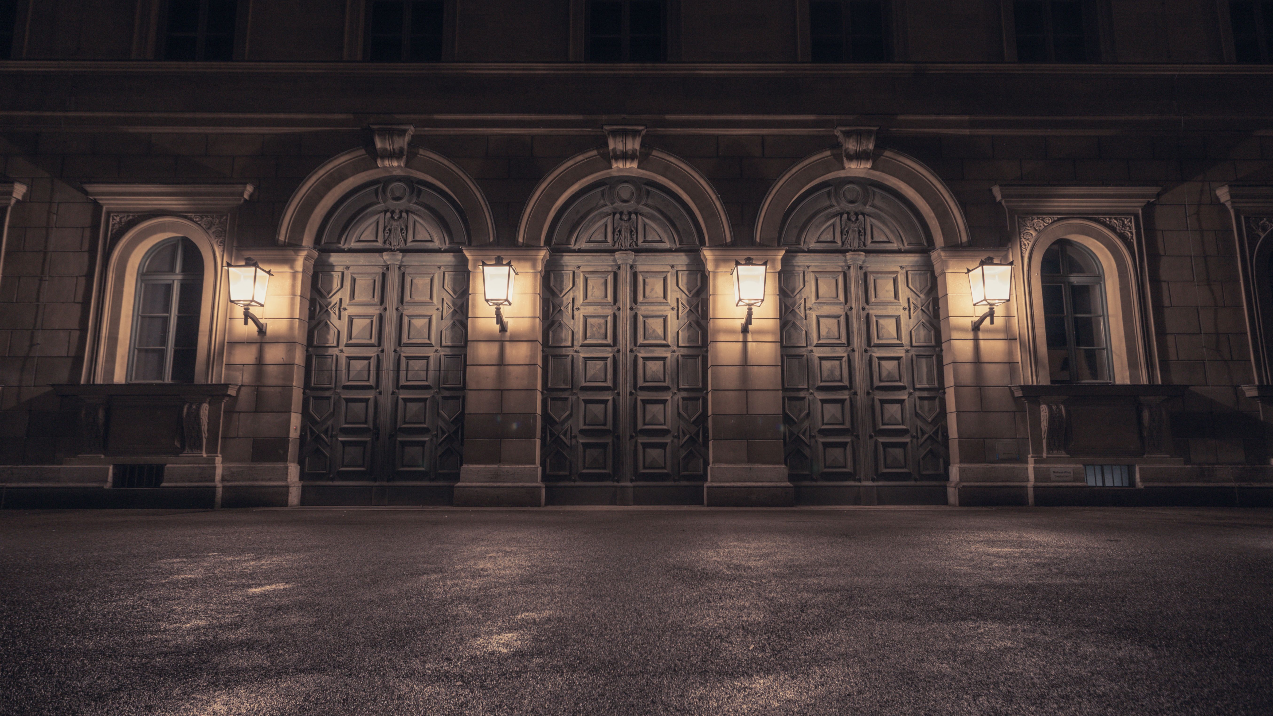 Elegante Steinfassade eines historischen Gebäudes in München, Bayern, nachts von Straßenlaternen beleuchtet.