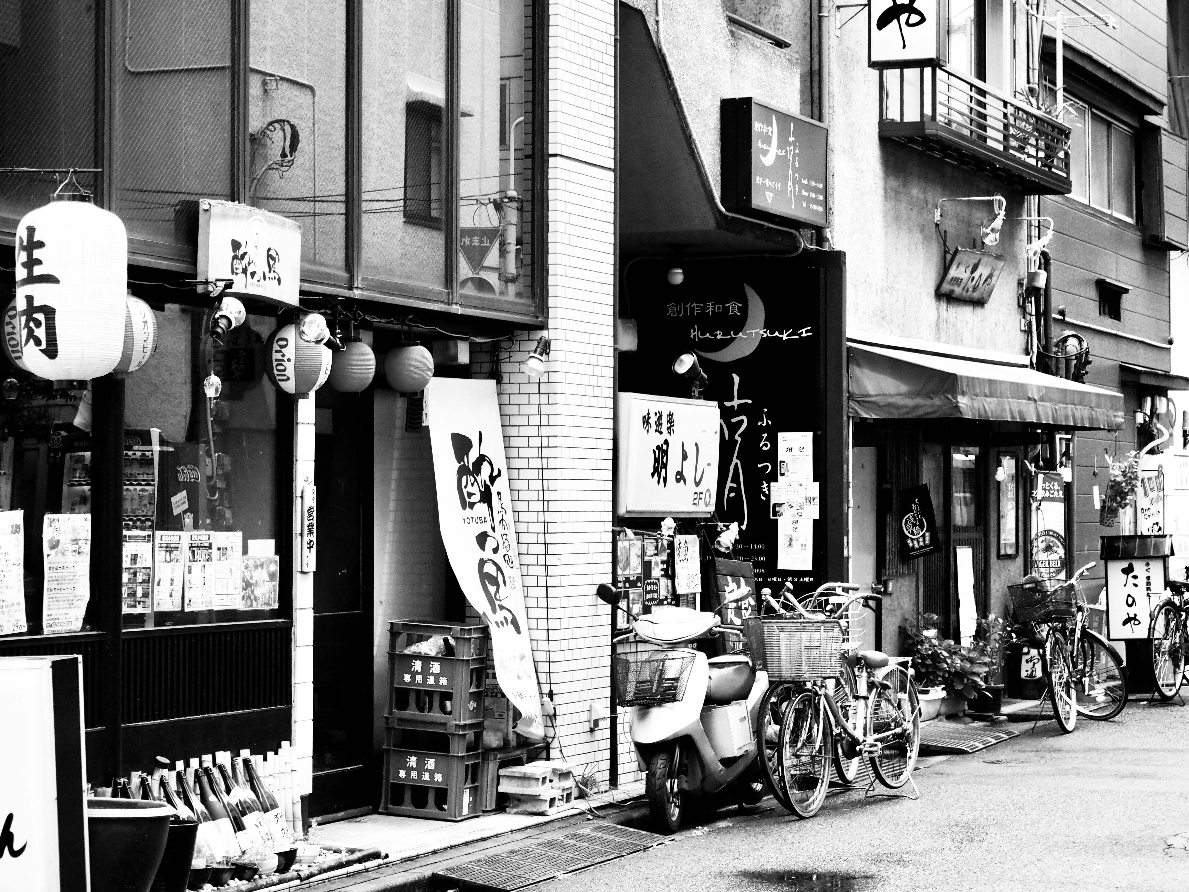 A monochrome street scene with traditional shops and parked bicycles in Japan.