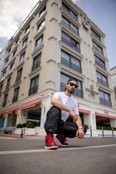 Young man squatting stylishly in front of an iconic building in Istanbul.