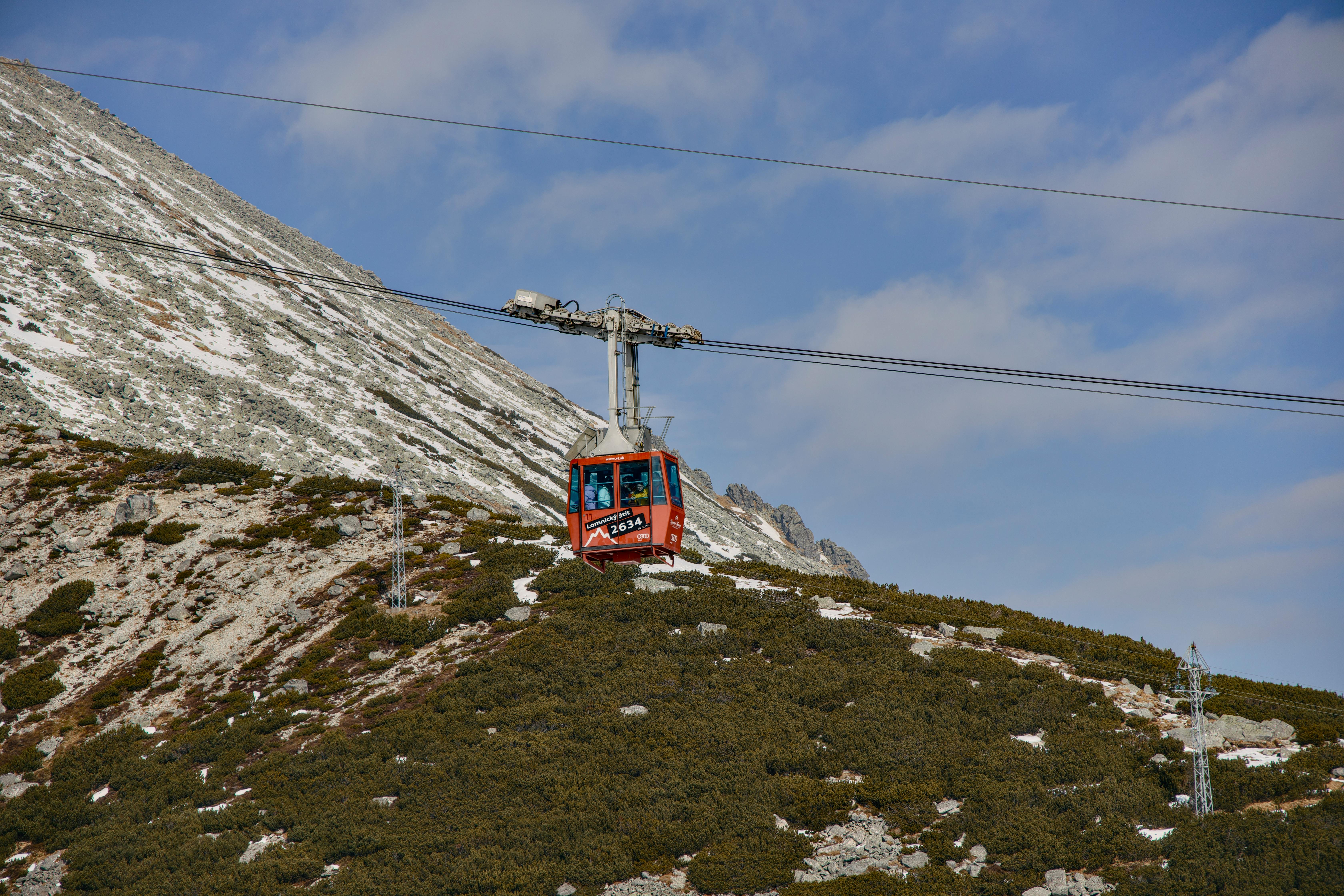 Red cable car ascending snowy Vysoké Tatry in Slovakia on a clear winter day.