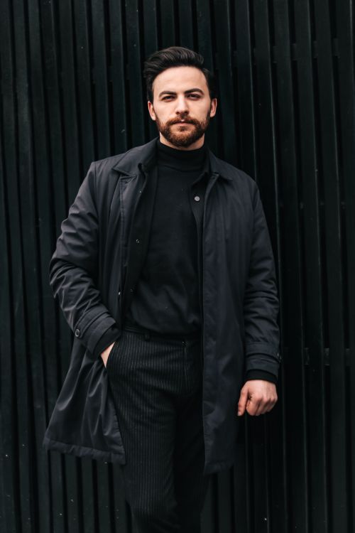 Free Portrait of a confident man in a stylish black outfit against a dark textured background. Stock Photo