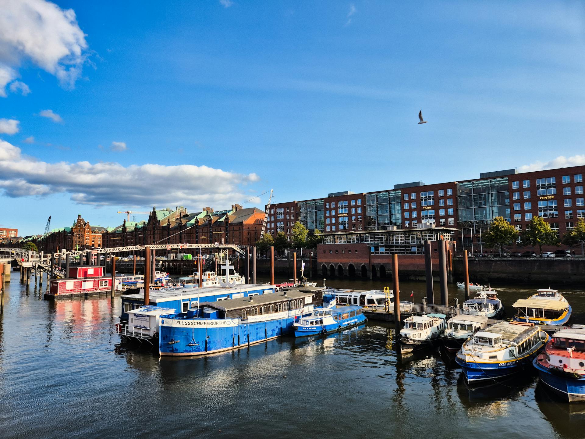 Colorful boats docked in Hamburg's historic warehouse district along the Elbe River.