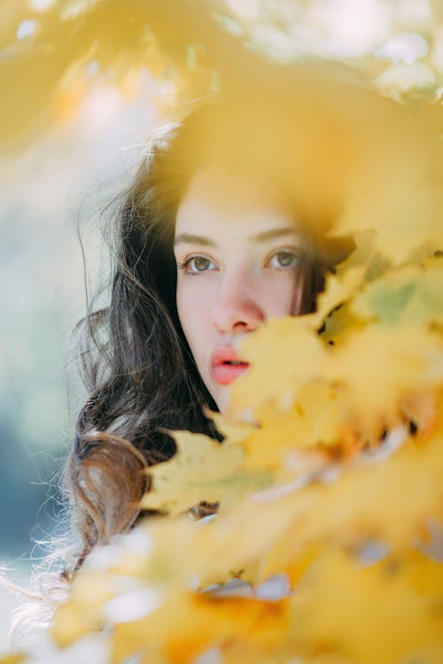 Selective Photo of Woman's Face Near Leaves