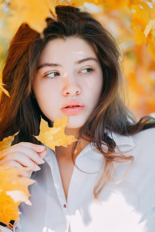 Photo of Woman Looking Away While Holding a Leaf