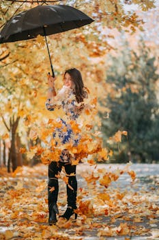 一位在公园里拿着伞微笑的妇女，伞上装饰着充满活力的秋叶