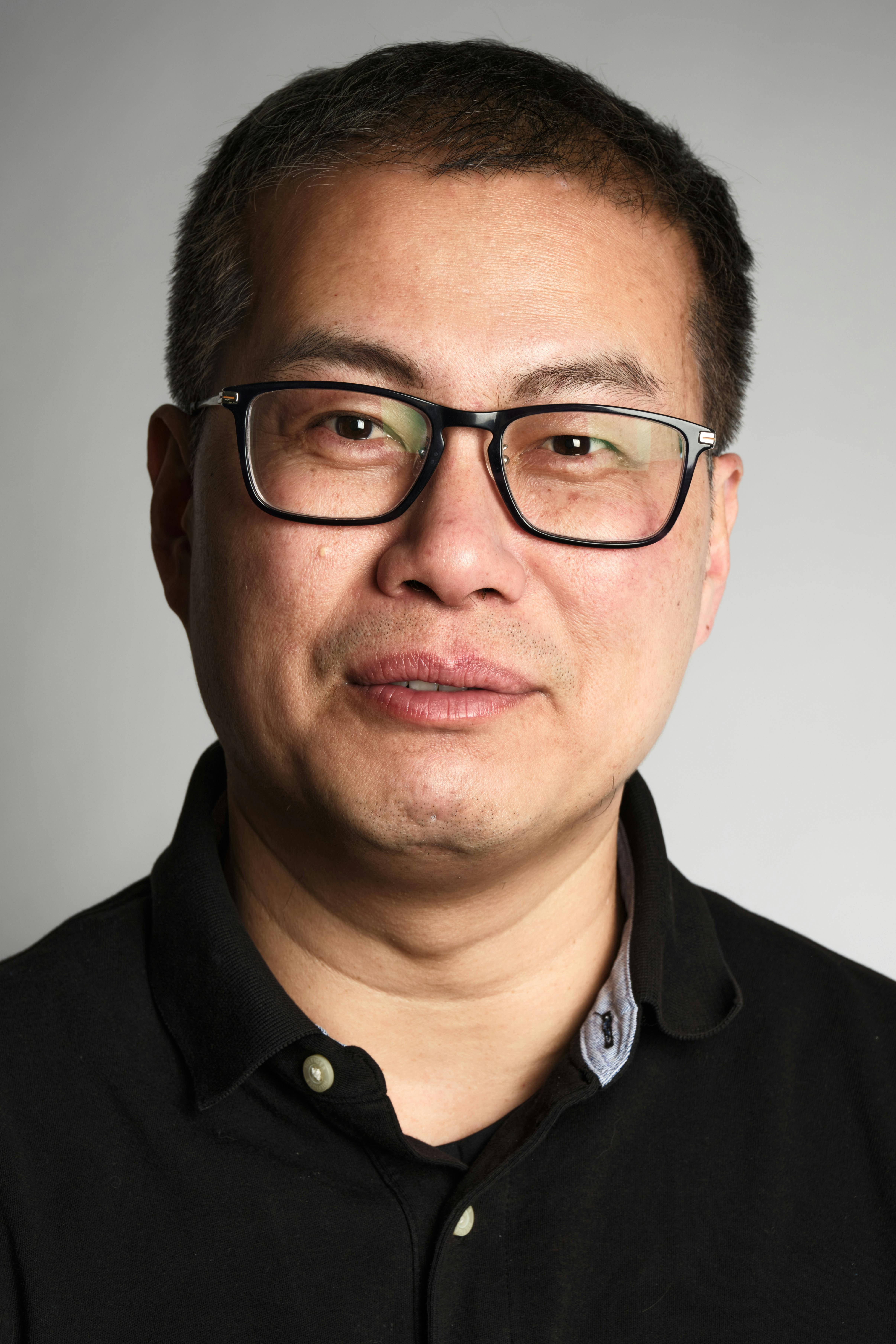 Portrait of a middle-aged man with glasses in a neutral setting.