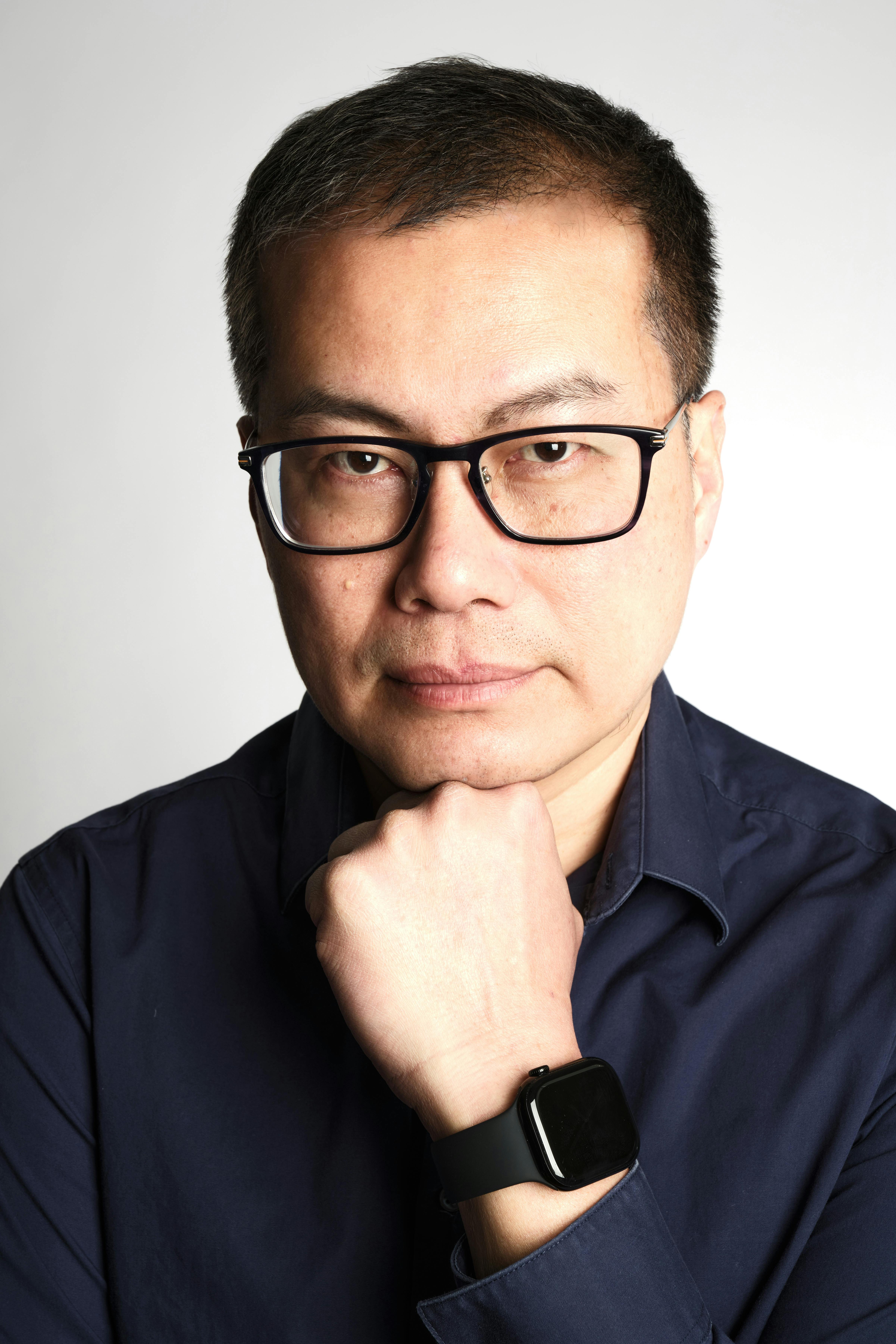 Portrait of a confident man with glasses in a dark shirt and smartwatch.