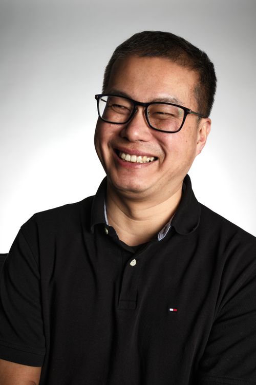 Free Portrait of a happy man wearing glasses and a black polo shirt, smiling warmly. Stock Photo