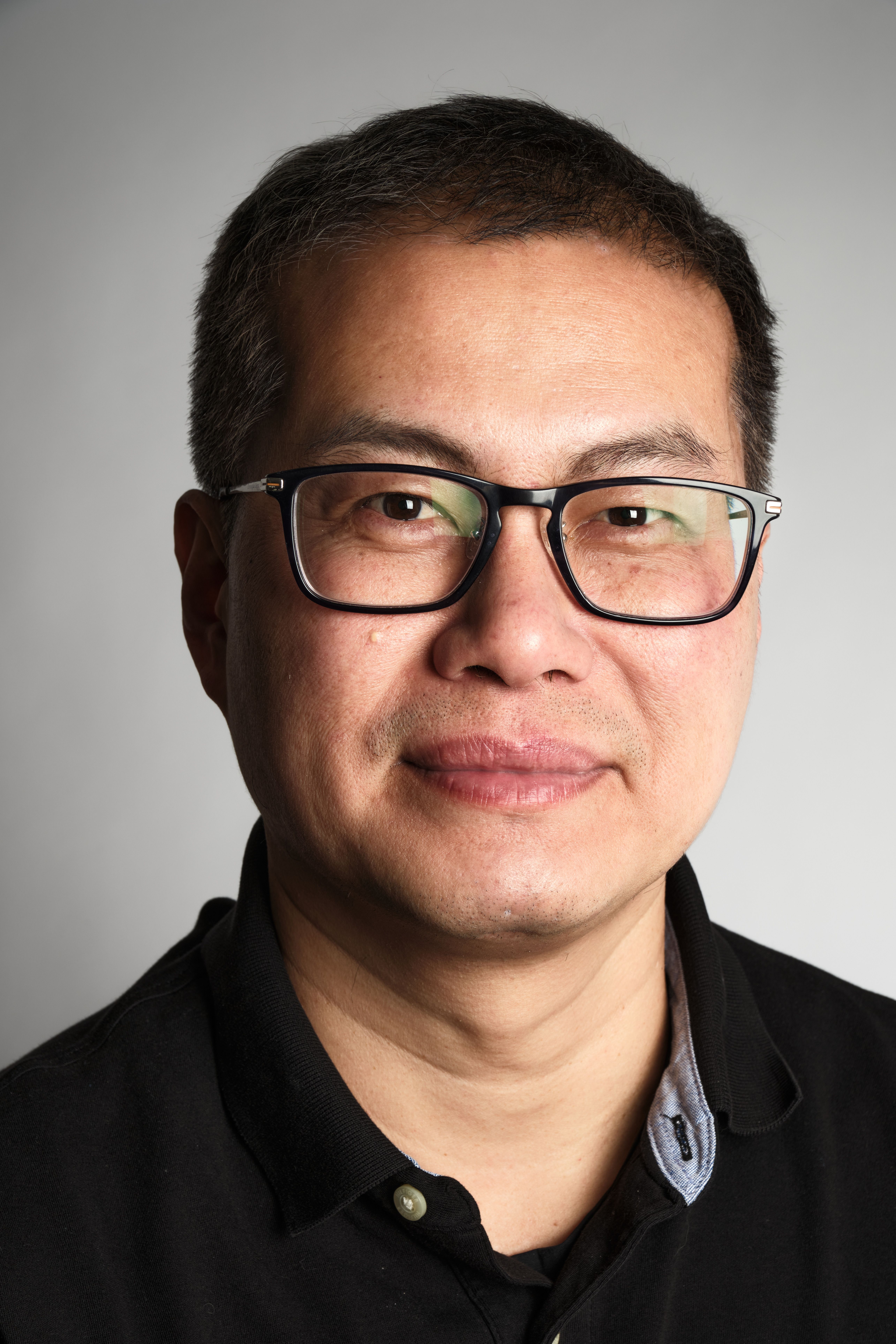 Close-up portrait of a middle-aged man in glasses, neutral background.