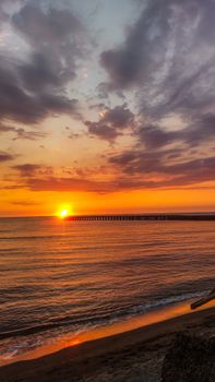 Peaceful beach sunset with vibrant colors and a scenic pier in the Ilocos Region, Philippines.
