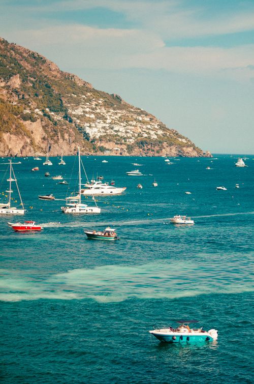 Free Turquoise waters and sailboats near a rocky Mediterranean coastline. Stock Photo