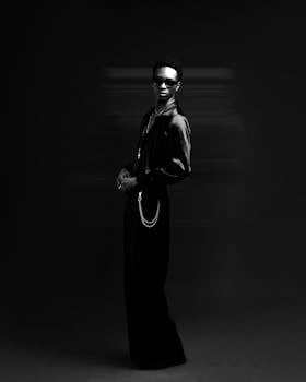 Artistic black and white portrait of a stylish individual wearing sunglasses.