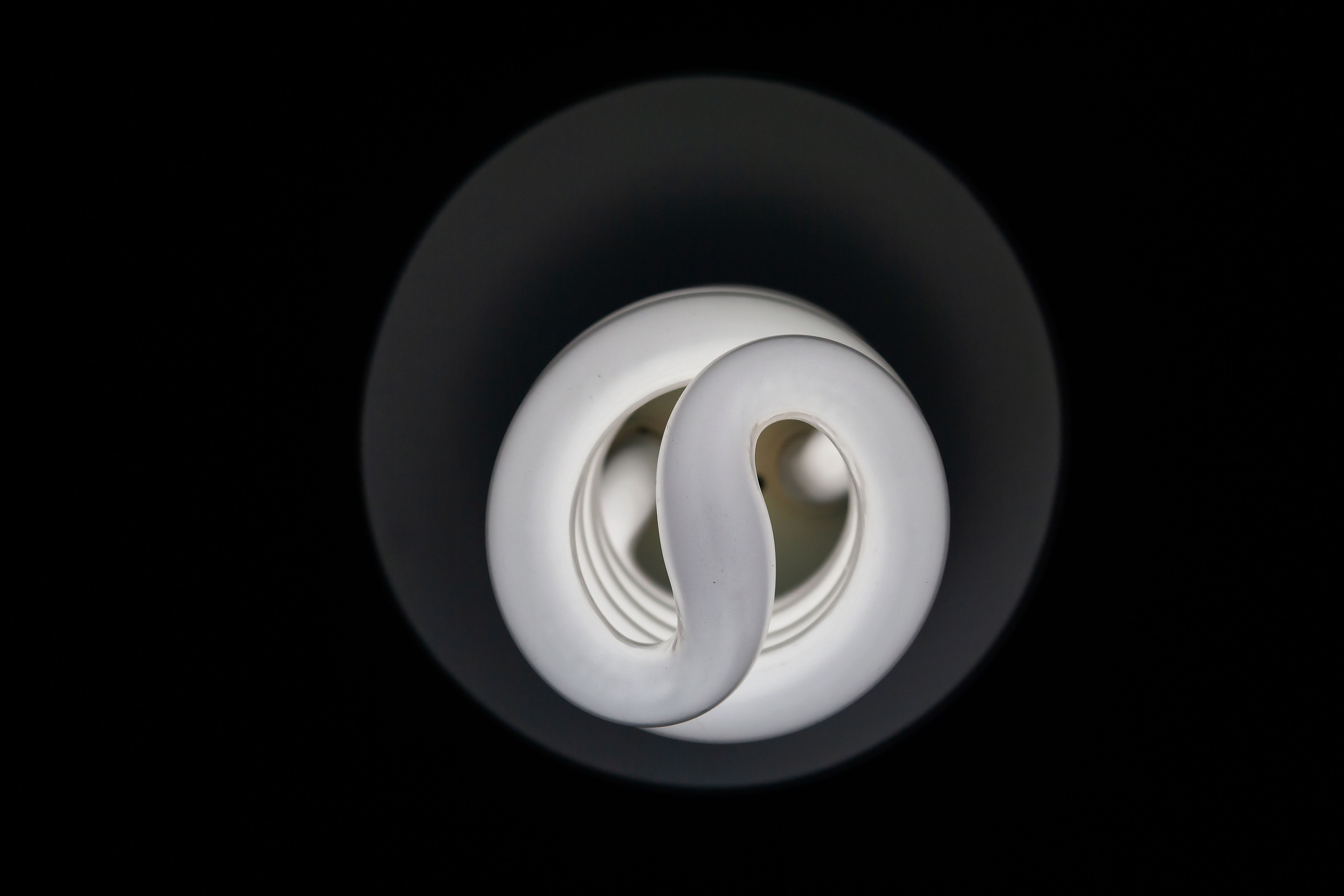 Vue détaillée d'une ampoule fluorescente compacte (CFL) sur un fond sombre, mettant en valeur sa conception en spirale.