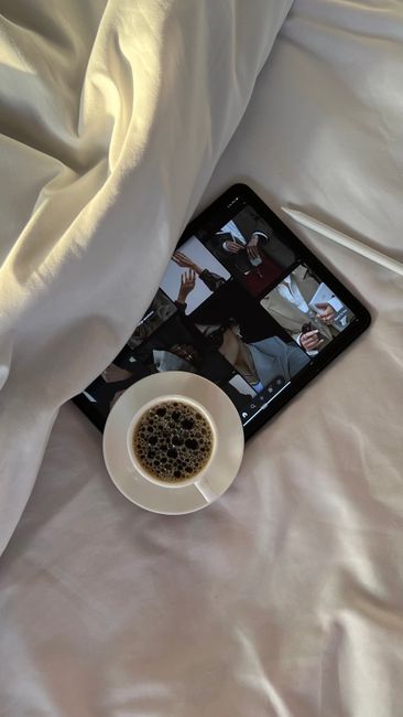 A cozy setup with a coffee cup next to a tablet on a bed.