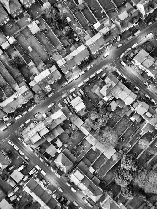 Free Black and white aerial view of a dense urban residential area with roads and houses. Stock Photo