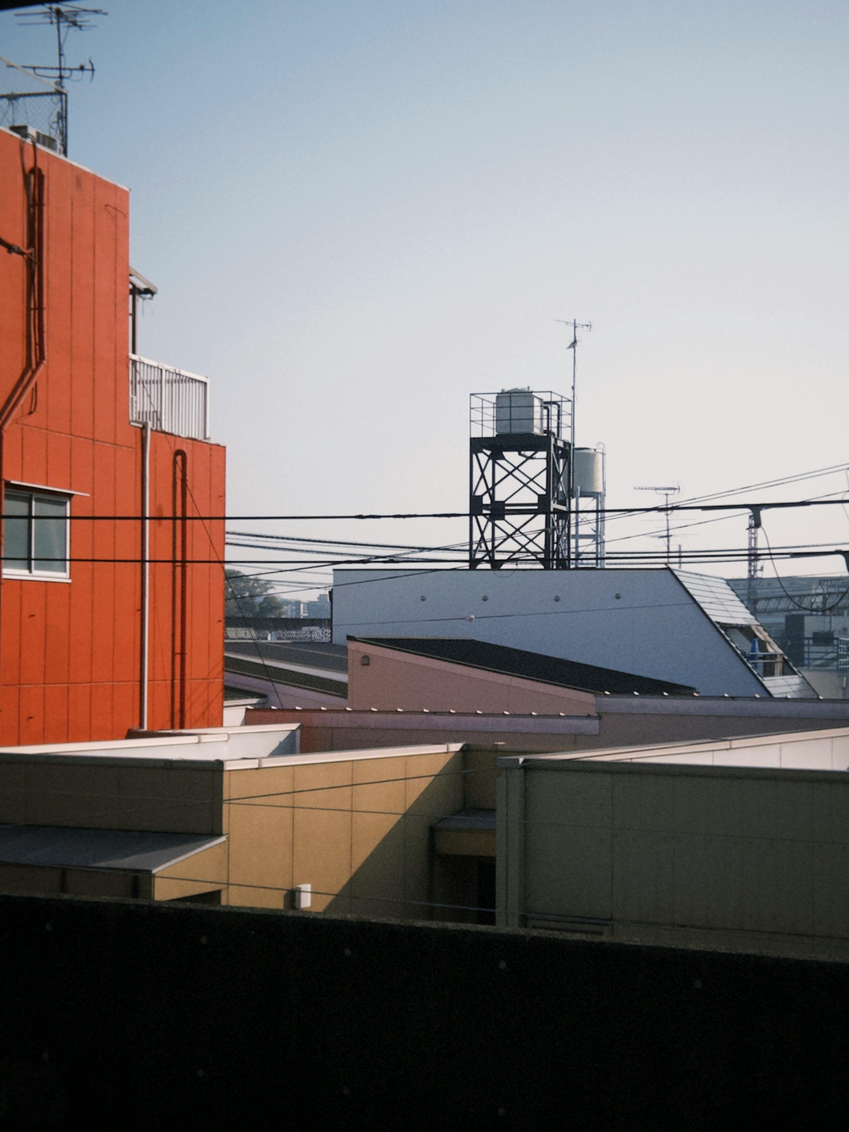 View of colorful urban rooftops with a water tower in the background on a clear day in Japan.