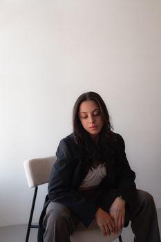 Serene portrait of a woman seated on chair against a minimalistic indoor setting.
