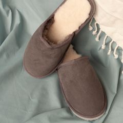 Brown suede-look backless slippers with fluffy cream linings on a blue sheet