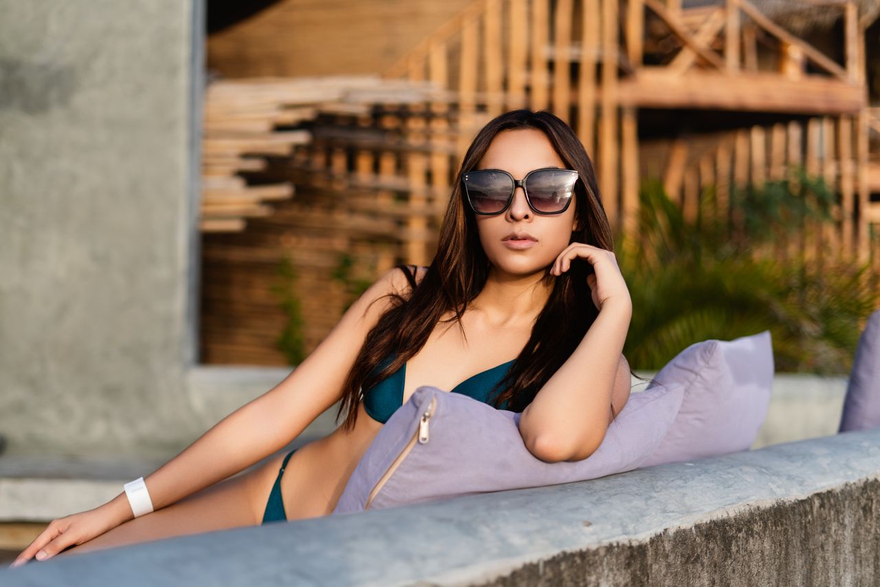 stylish woman in a bikini lounging outdoors enjoying the sun by the be