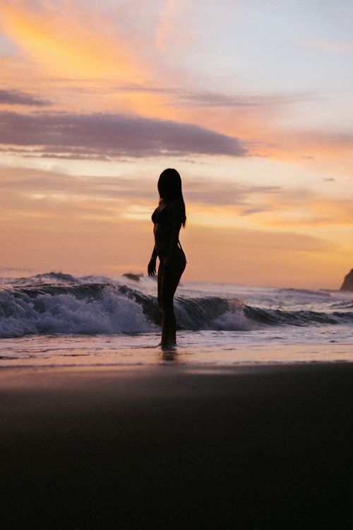 Woman in Bikini Walking on Sea Shore at Sunset · Free Stock Photo