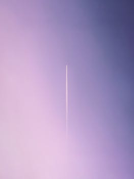 Airplane contrail against a pink and purple pastel sky in Amman, Jordan.