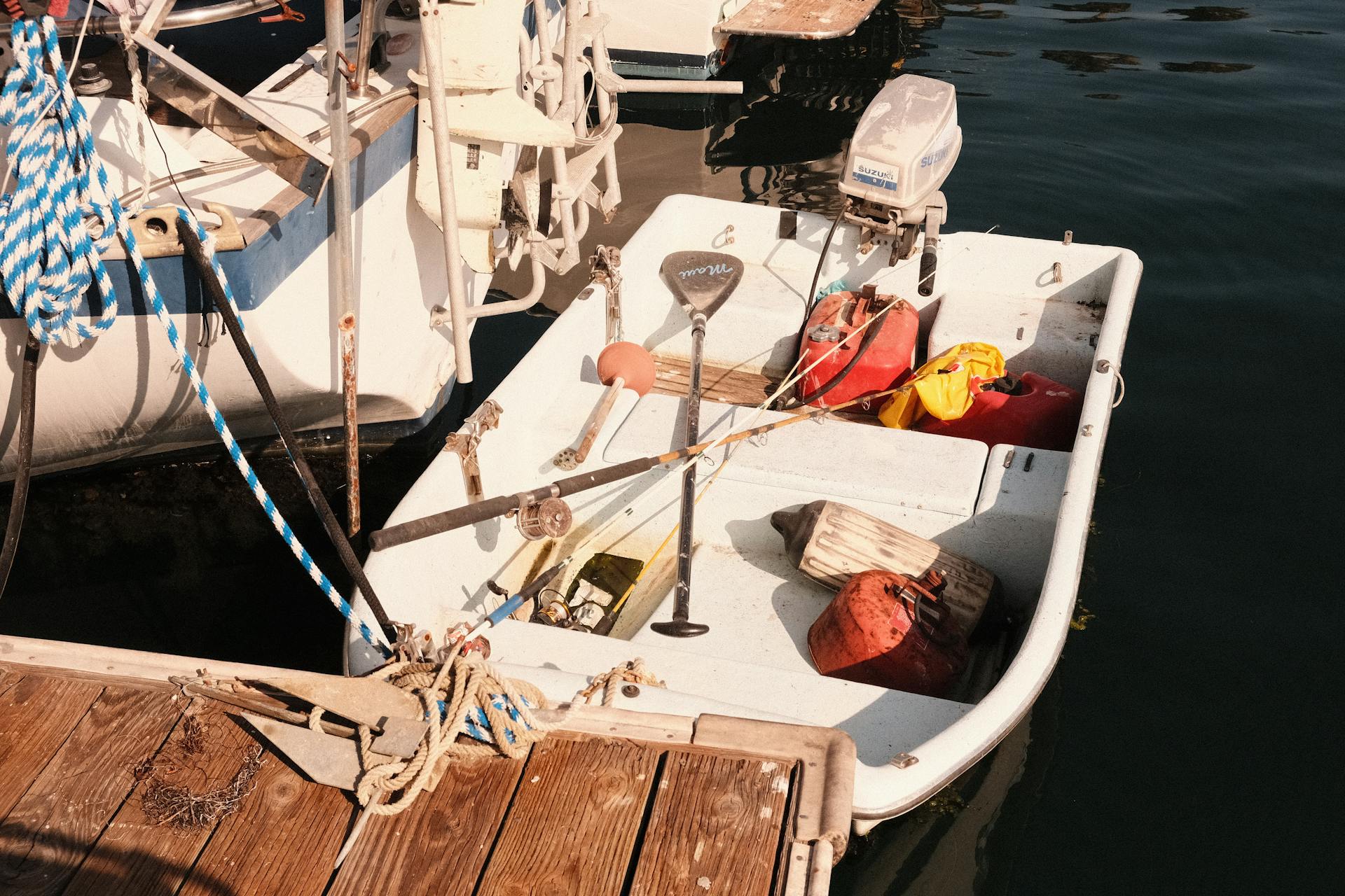 A small boat tied up at a marina dock with nautical equipment on a sunny day.