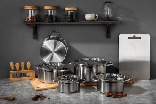 Stylish kitchen setup featuring stainless steel pots and kitchen accessories on a gray background.