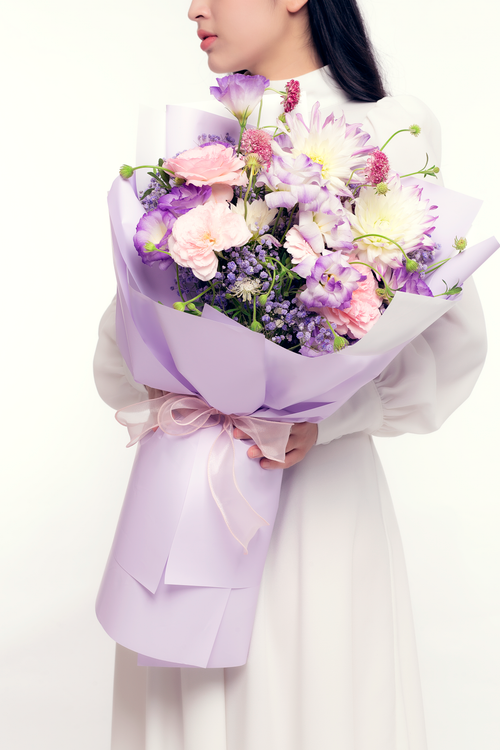 Free A woman in a white dress holding a beautiful pastel flower bouquet, exuding elegance and simplicity. Stock Photo
