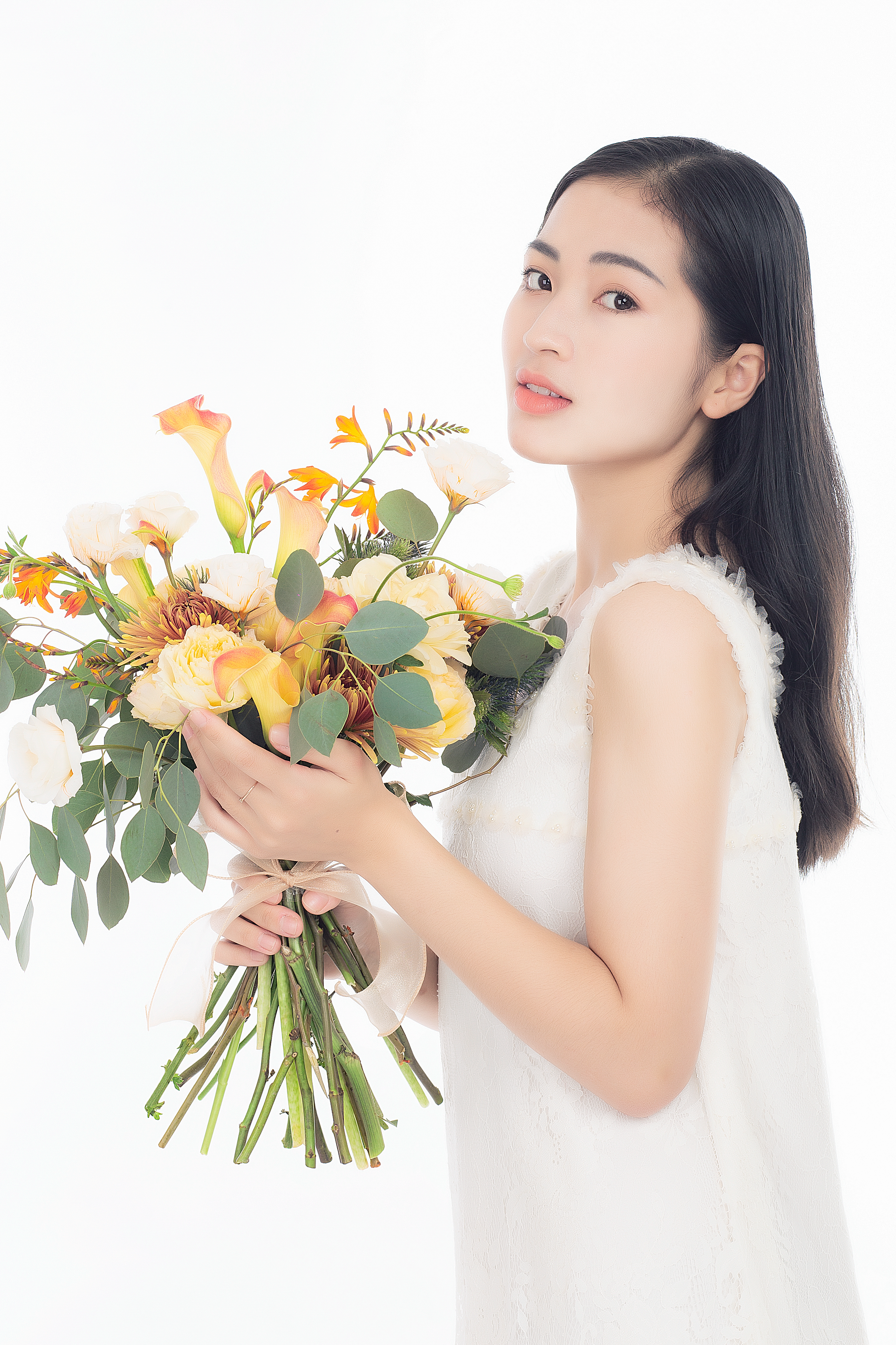 Elegant woman in white holding a vibrant autumn flower bouquet.