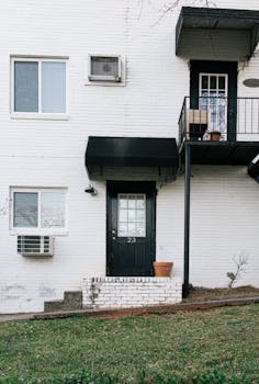 Simple white brick apartment facade with black door in Atlanta.