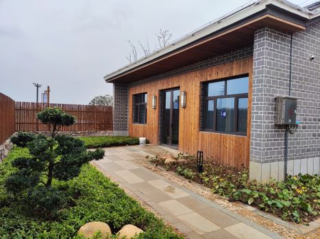 Contemporary single-story house with wood and brick design surrounded by a neat garden path.