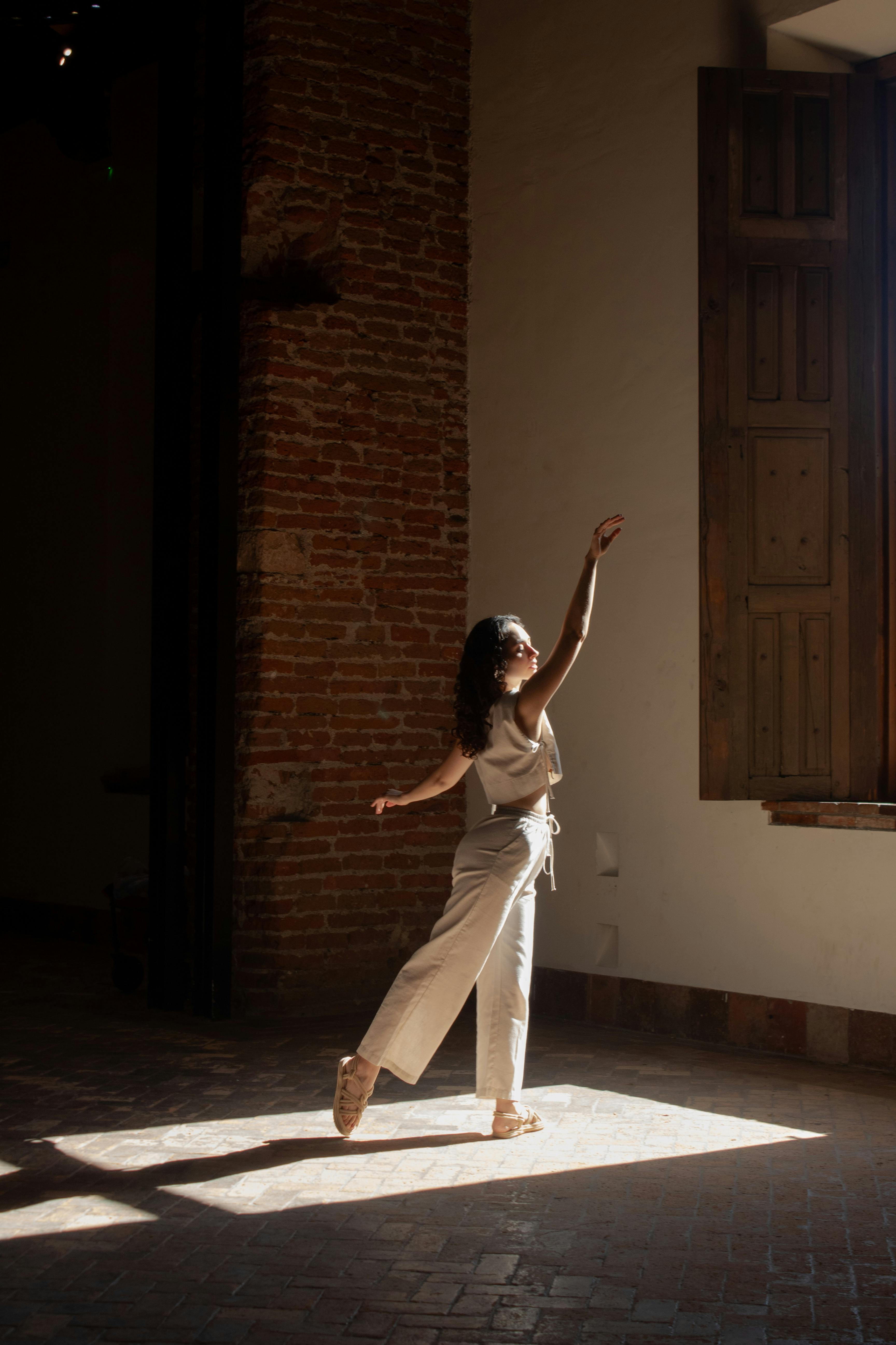 A graceful dancer performs in a sunlit room, emphasizing fluidity and art.