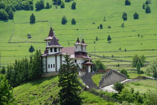 Beautiful countryside church set amidst a vibrant green landscape in summer.