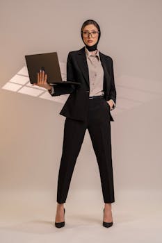 Professional businesswoman in stylish suit holding laptop, exuding confidence and empowerment.