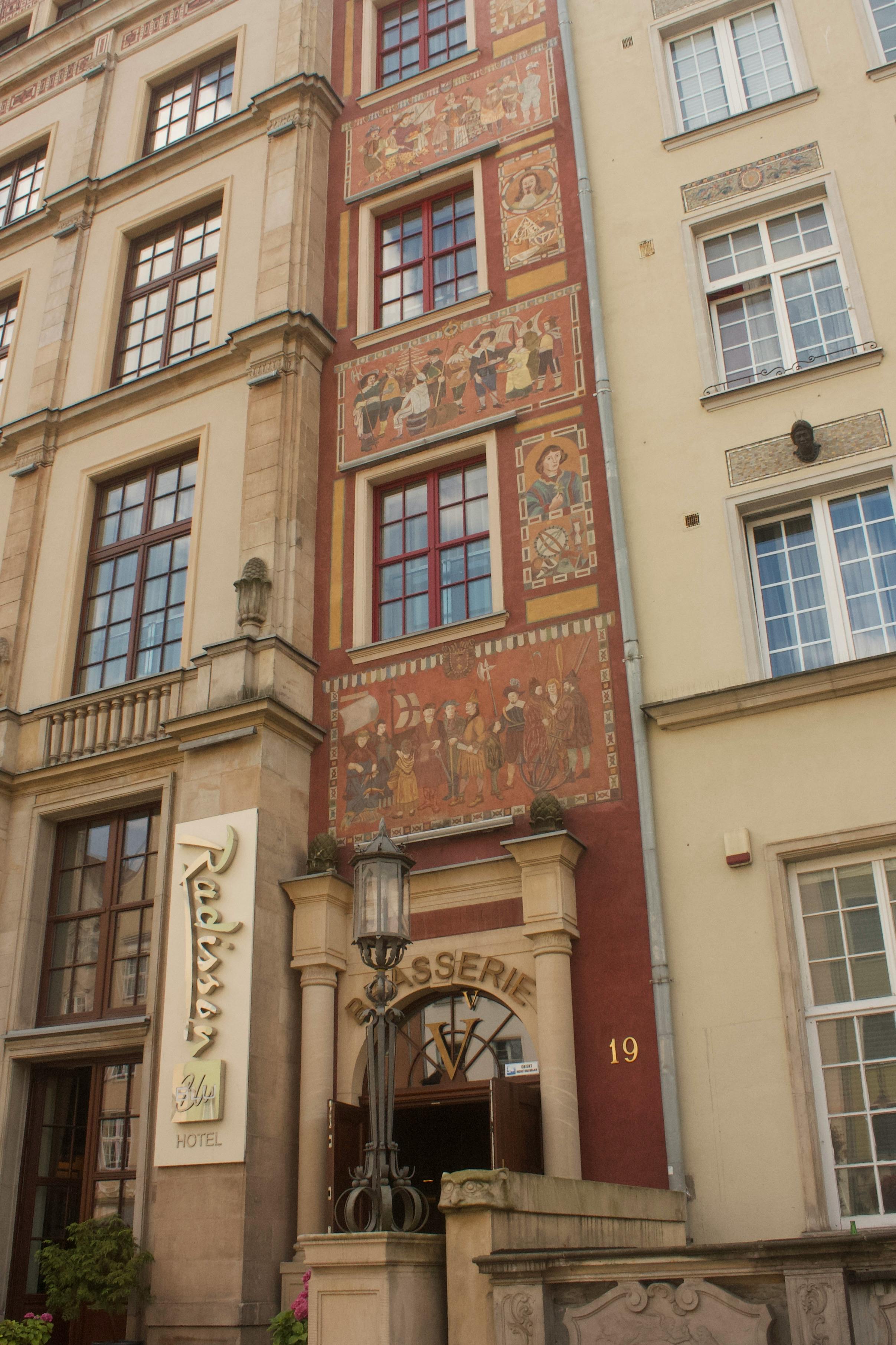A historic building with decorative murals on a brasserie facade in a European city.
