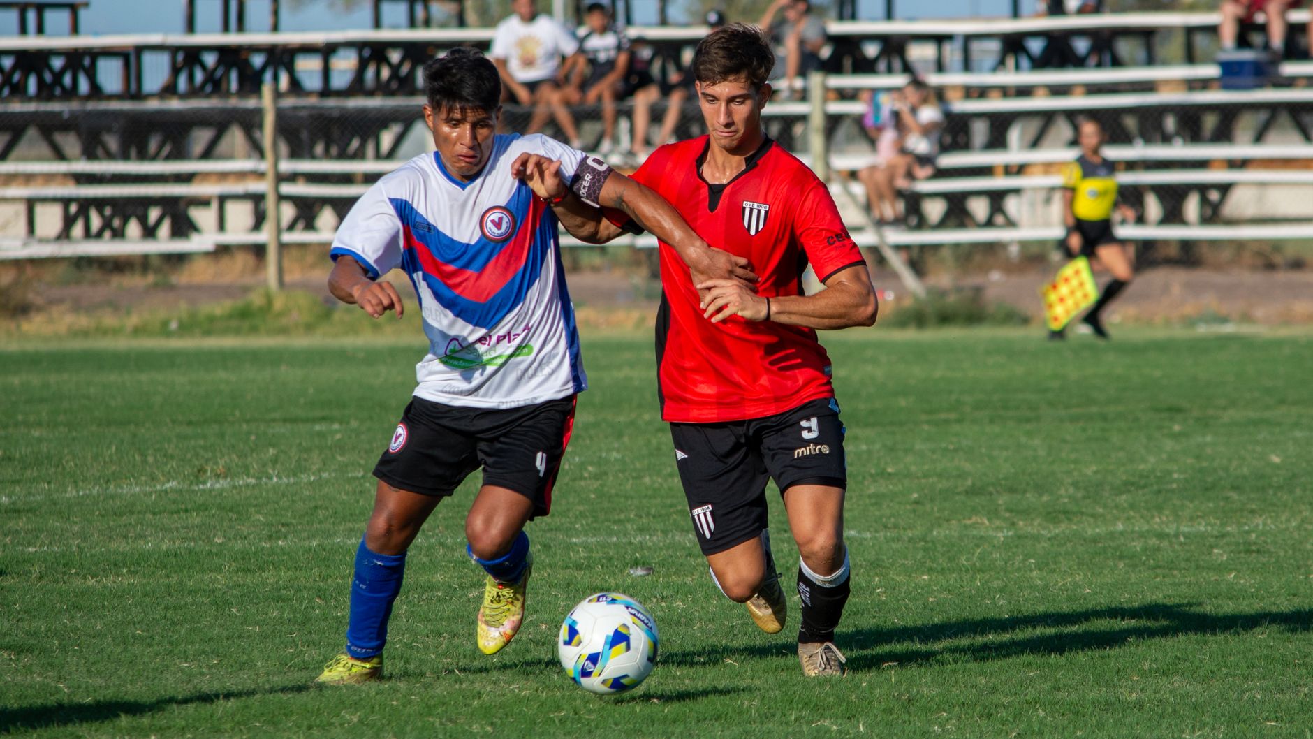 Two soccer players competing for the ball during a daytime match outdoors.