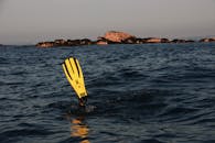 一名潜水员在岩石岛屿附近的海水中探索，长着突出的黄色鳍