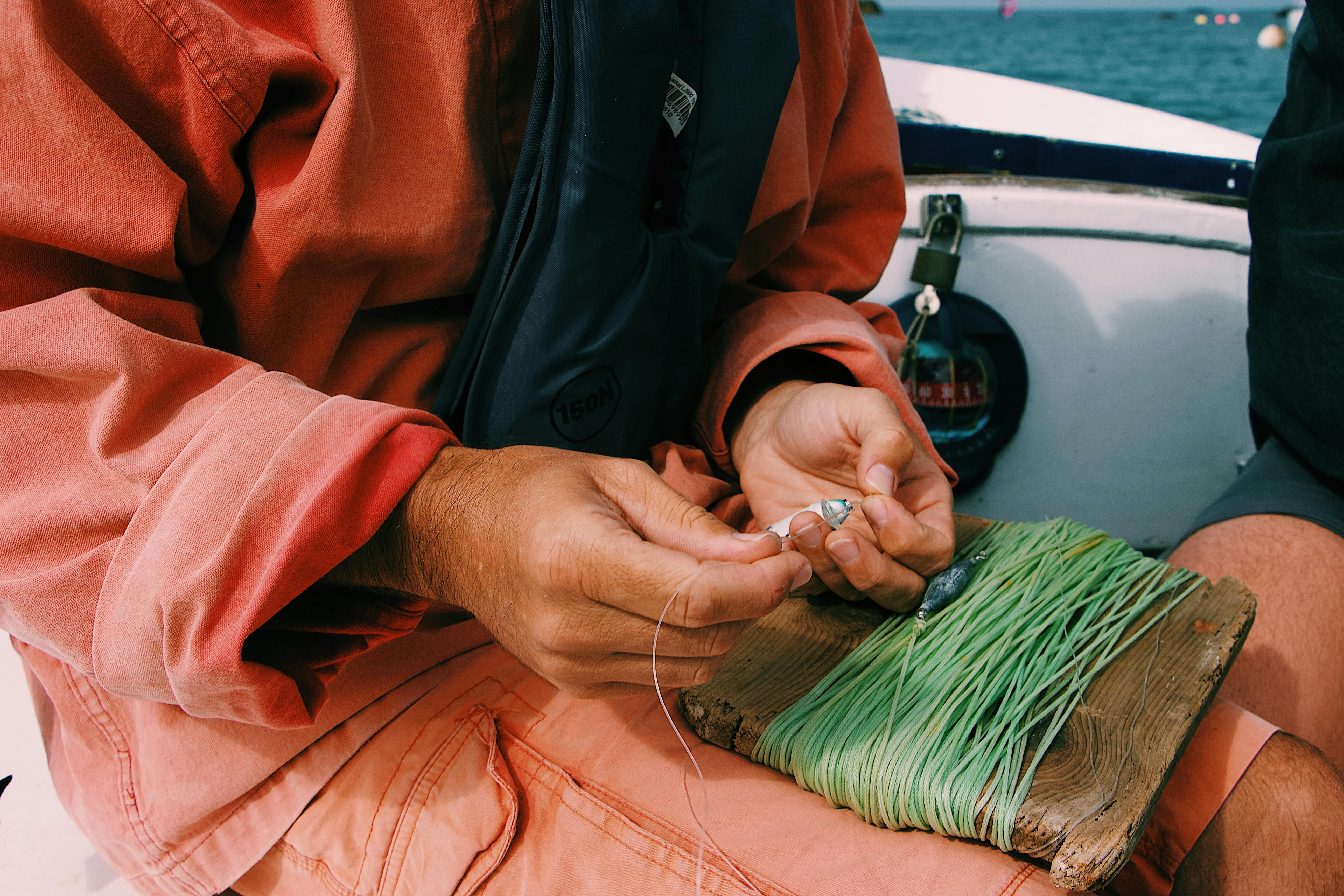 Close-up of a man setting up fishing line on a boat in the daytime.