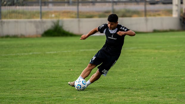 Young adult soccer player skillfully kicking the ball on the field during a match.
