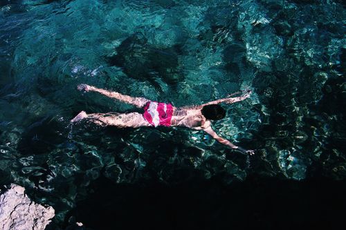 Free Person swimming in crystal clear water, captured from above, showcasing aquatic leisure and recreation. Stock Photo