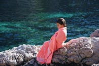 一个裹着毛巾的年轻女孩坐在宁静的湖边沉思，享受着户外活动