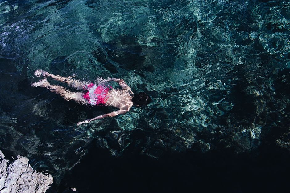 A swimmer in red shorts dives in clear waters, capturing vivid reflections and movement.
