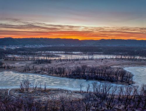 Free Frozen river landscape with barren trees at sunrise in Wabasha, Minnesota, creating a serene winter scene. Stock Photo