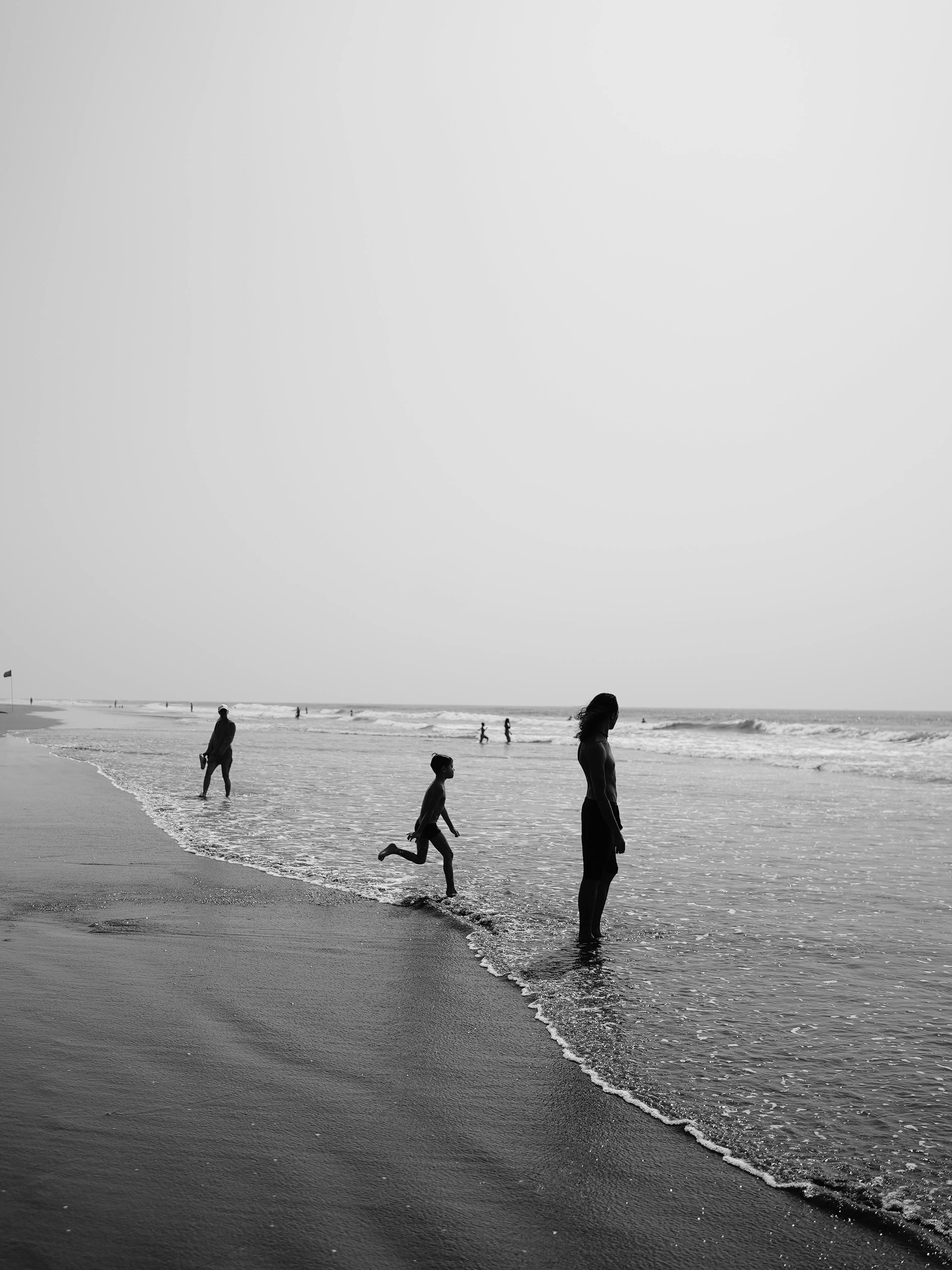 Silhouetted figures on a serene beach in Goa, India during the day.